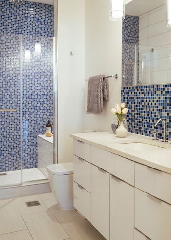 A bathroom with white cabinets and a blue and white tiled wall